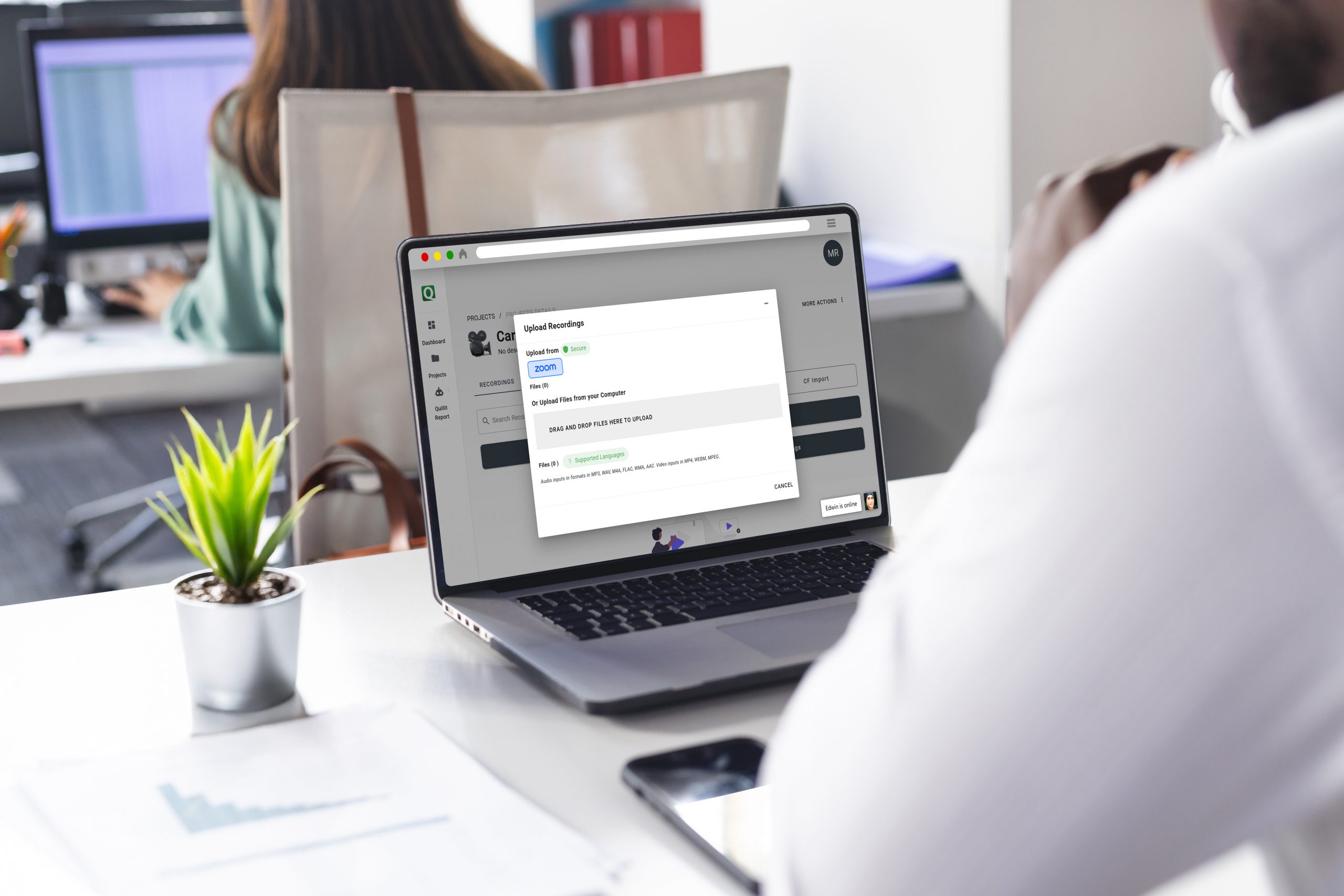 A man sitting at a desk, focused on his laptop, with a notepad and pen beside him